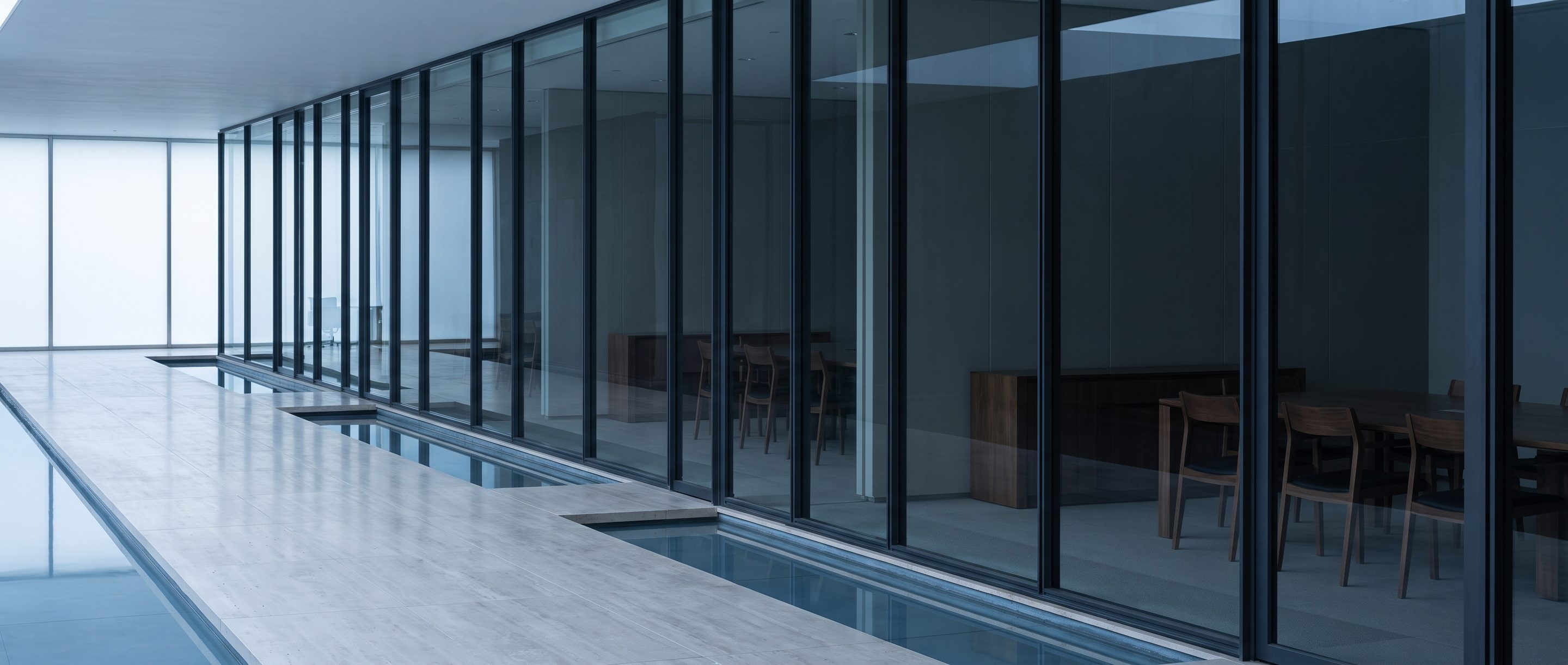 A row of glass-walled meeting rooms along a quiet corridor.