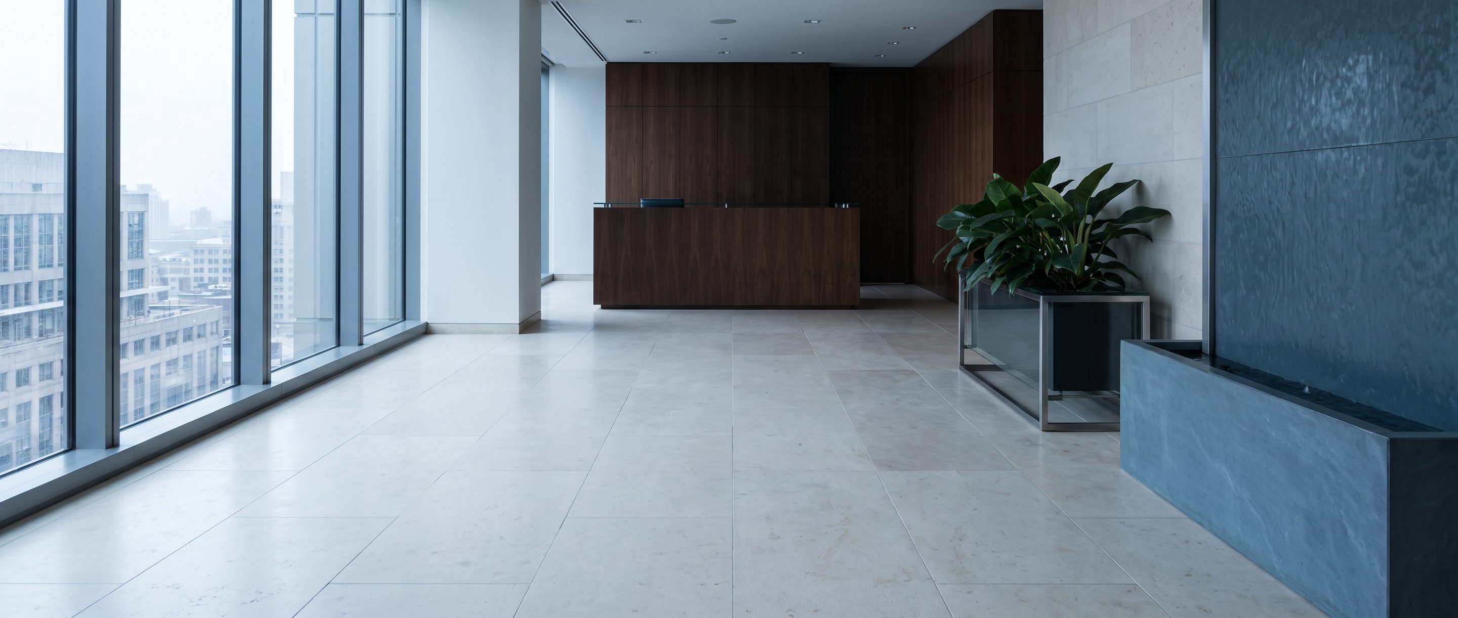 A quiet stone-and-glass office lobby, pale limestone floor.