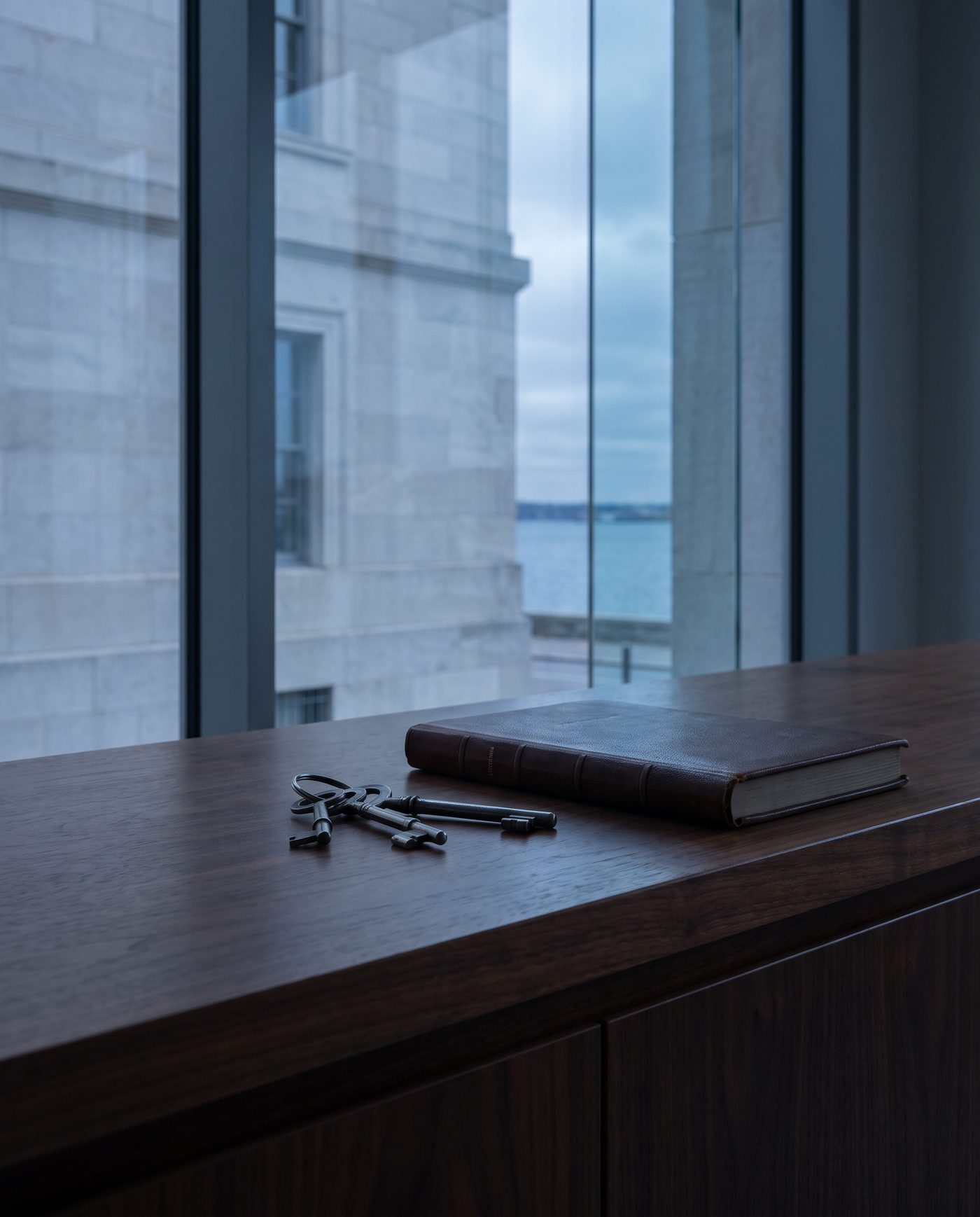 A single set of shop keys on a walnut counter beside a closed ledger.