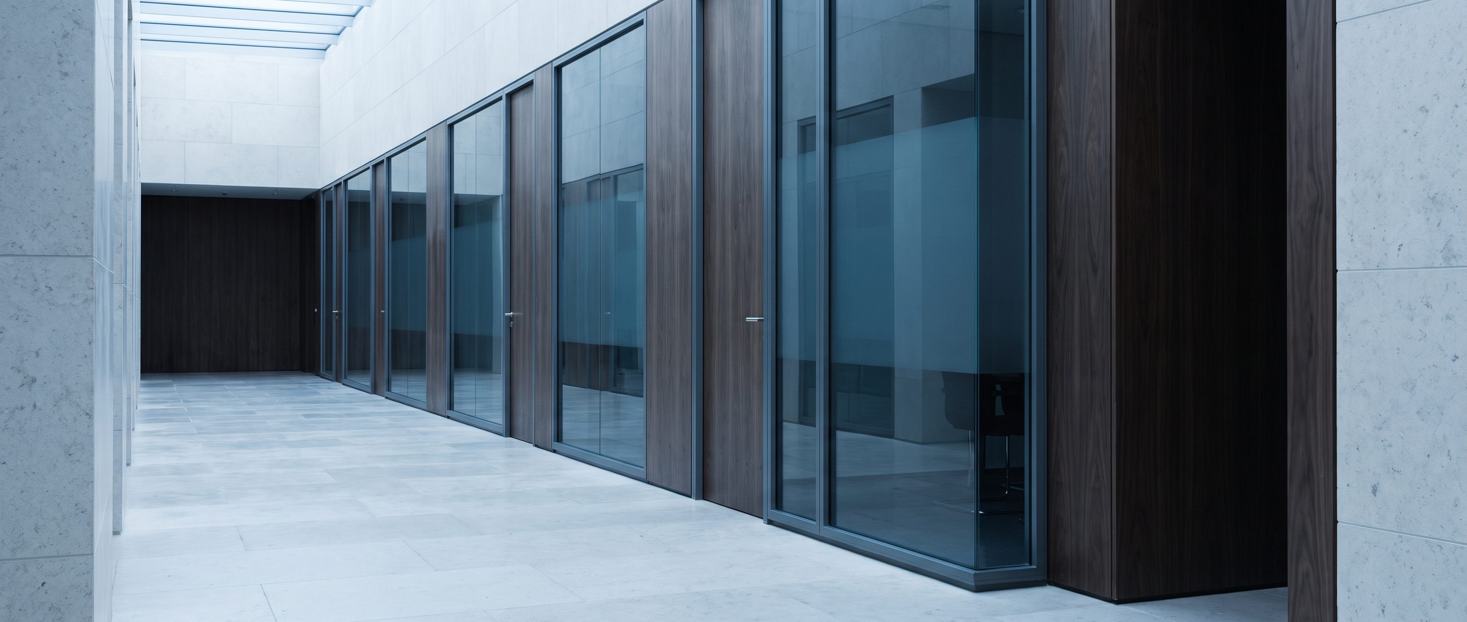 A row of glass-walled meeting rooms along a quiet corridor.