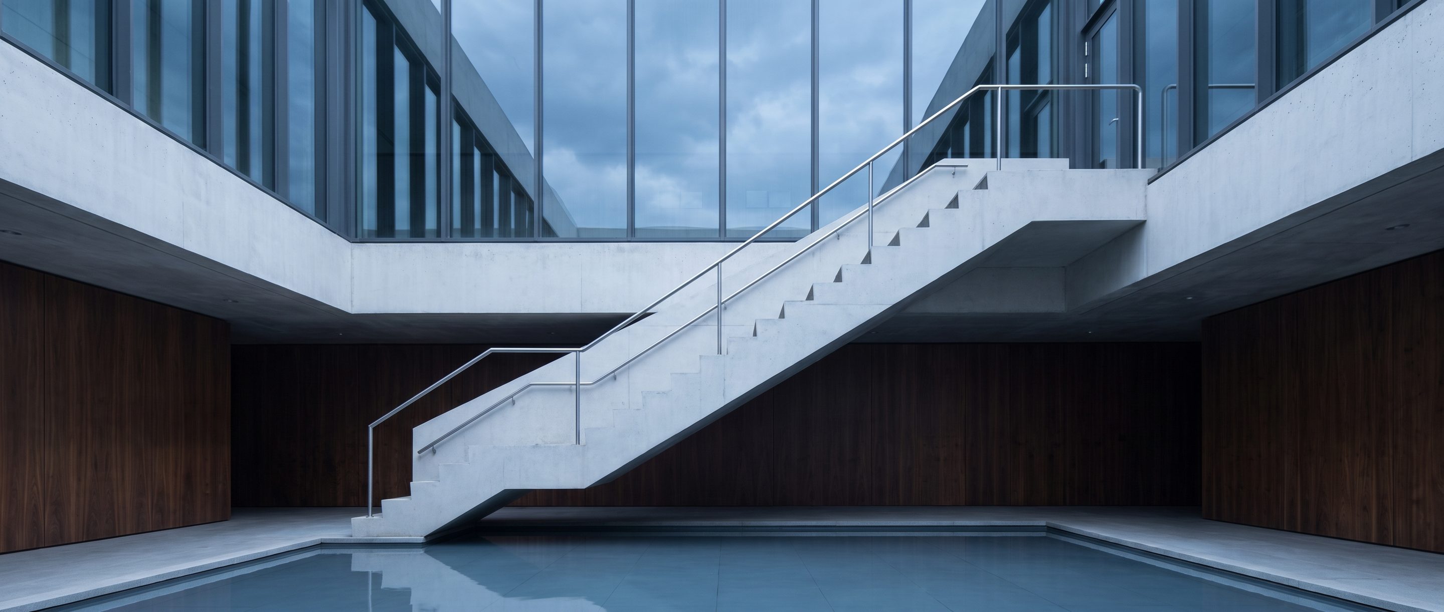 The underside of a pale concrete stair in an empty atrium.