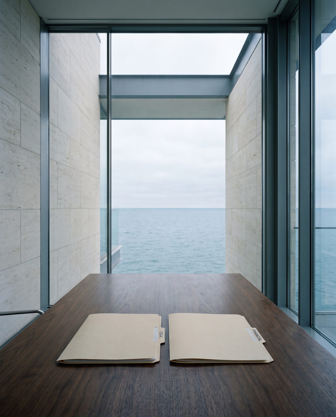 Two folders, one tabbed legal and one tabbed financial, aligned on a walnut table.