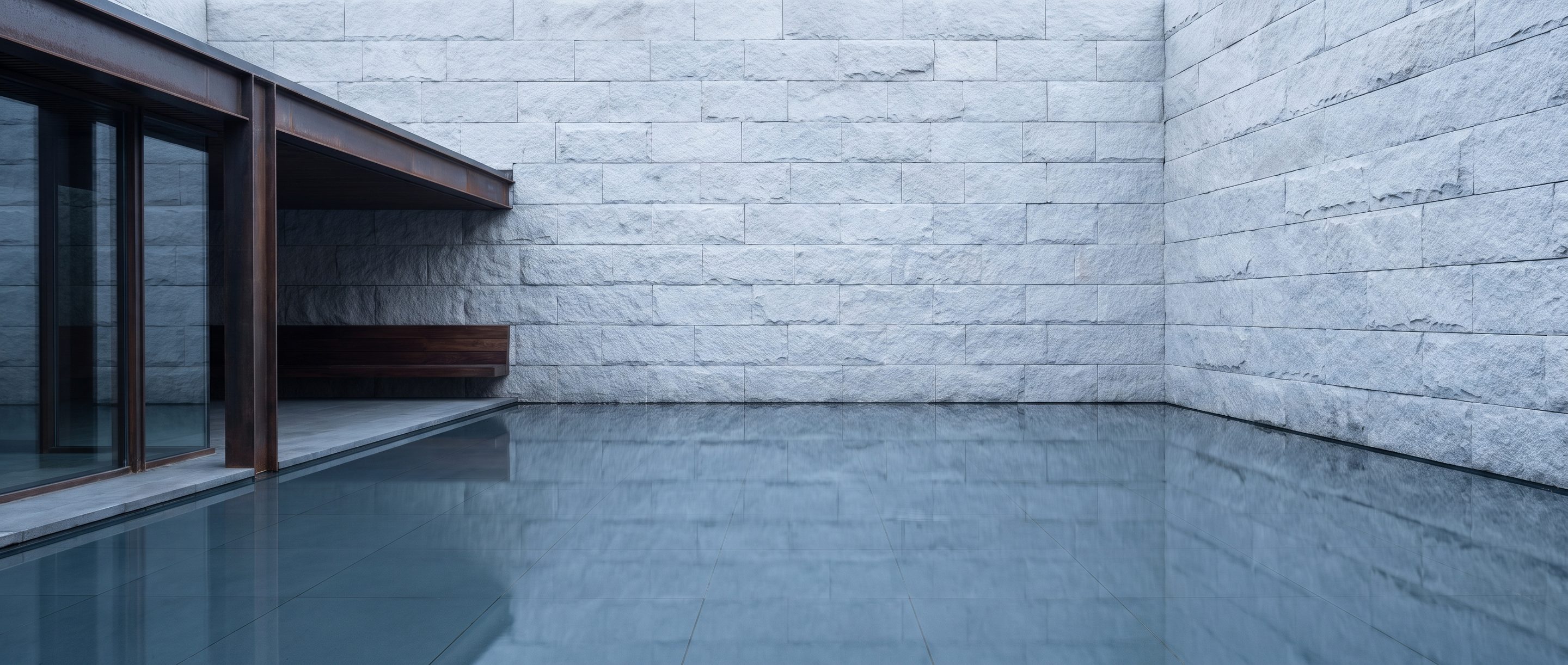 A still reflecting pool against a plain stone wall, overcast light.