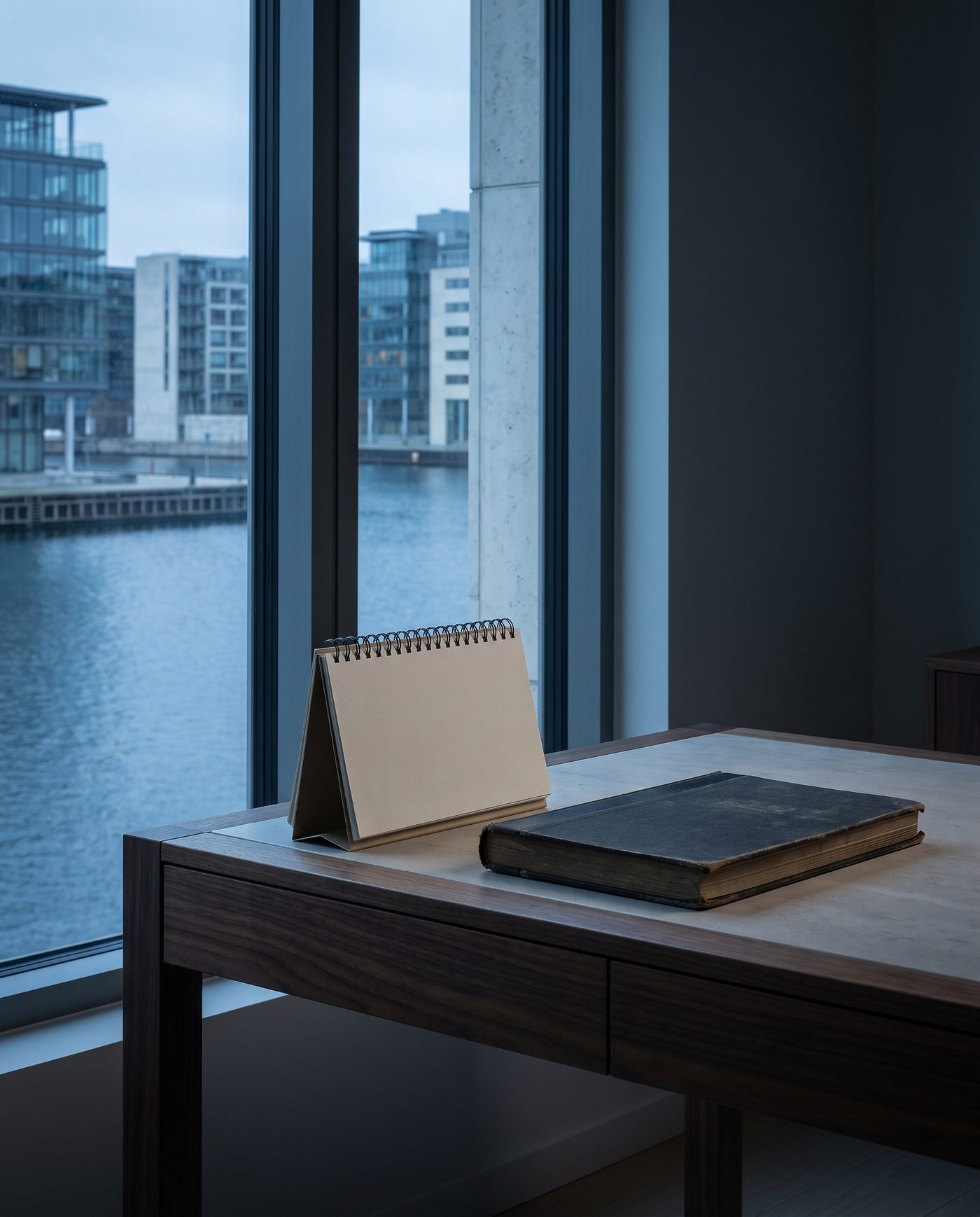 A desk calendar turned to a blank month beside a closed ledger.