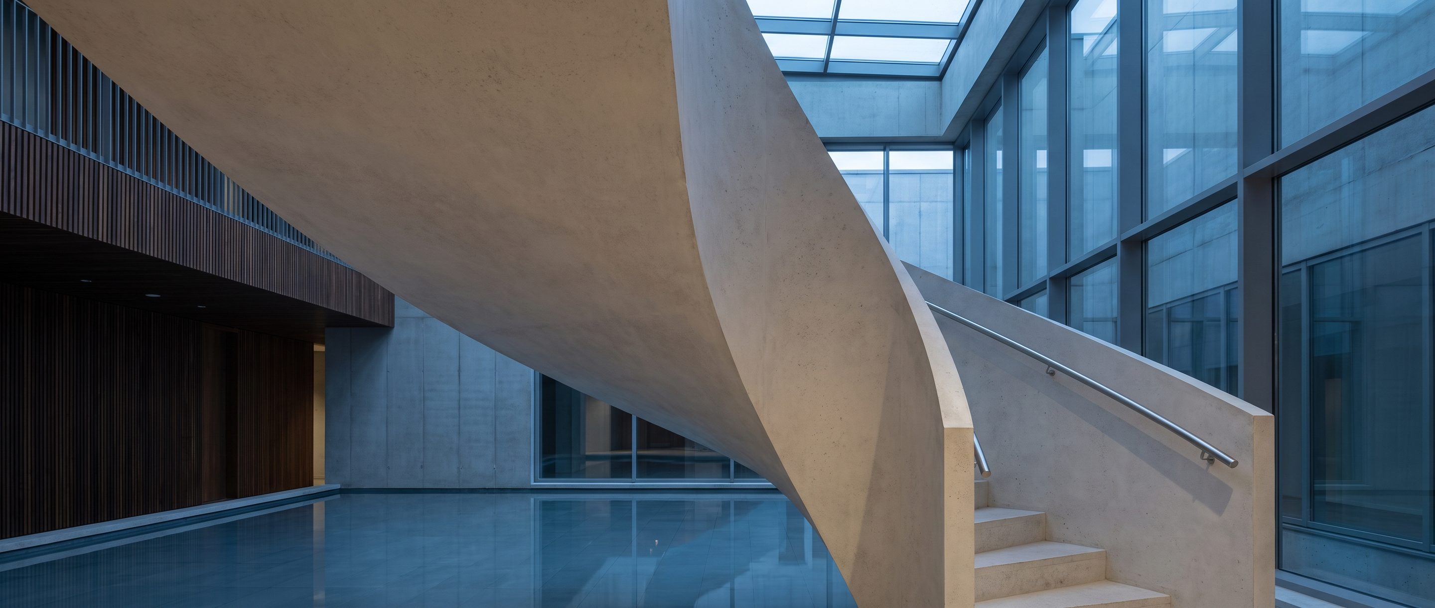 The underside of a pale concrete stair in an empty atrium.