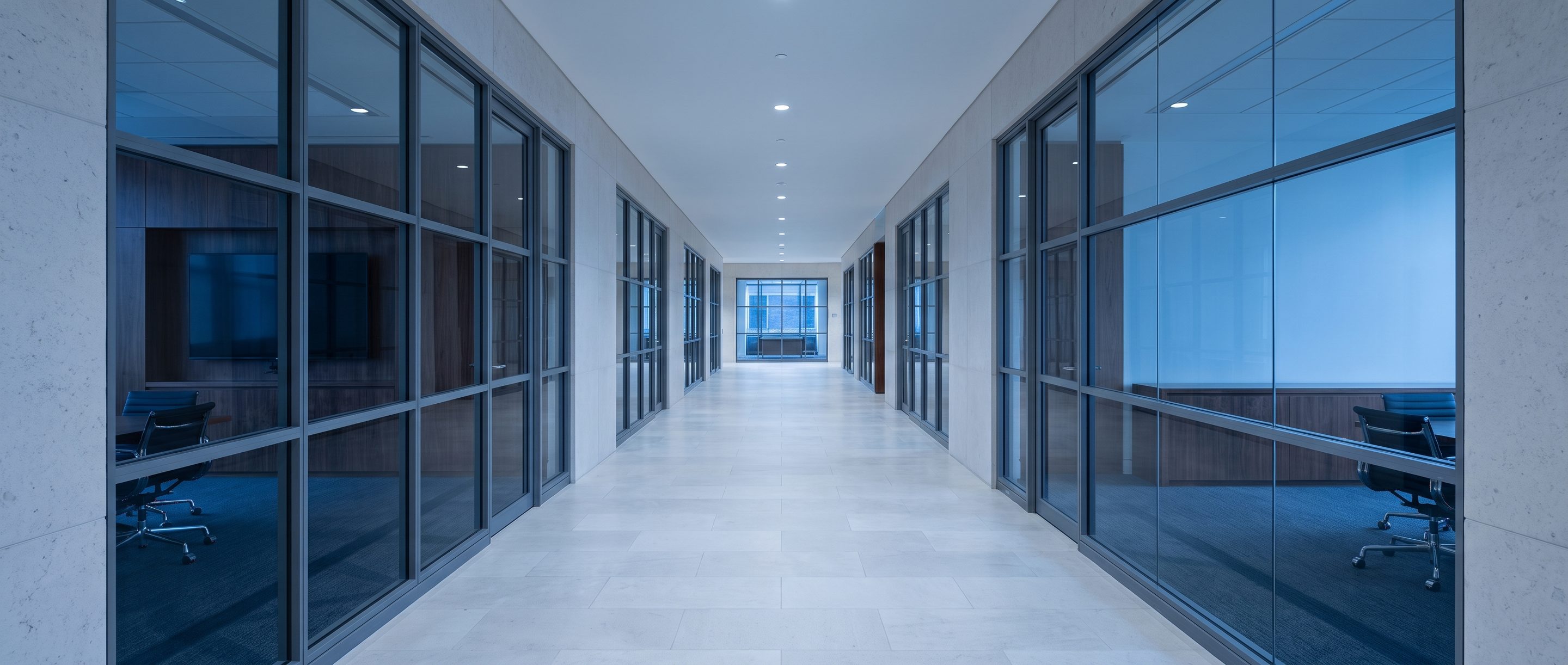 A row of glass-walled meeting rooms along a quiet corridor.