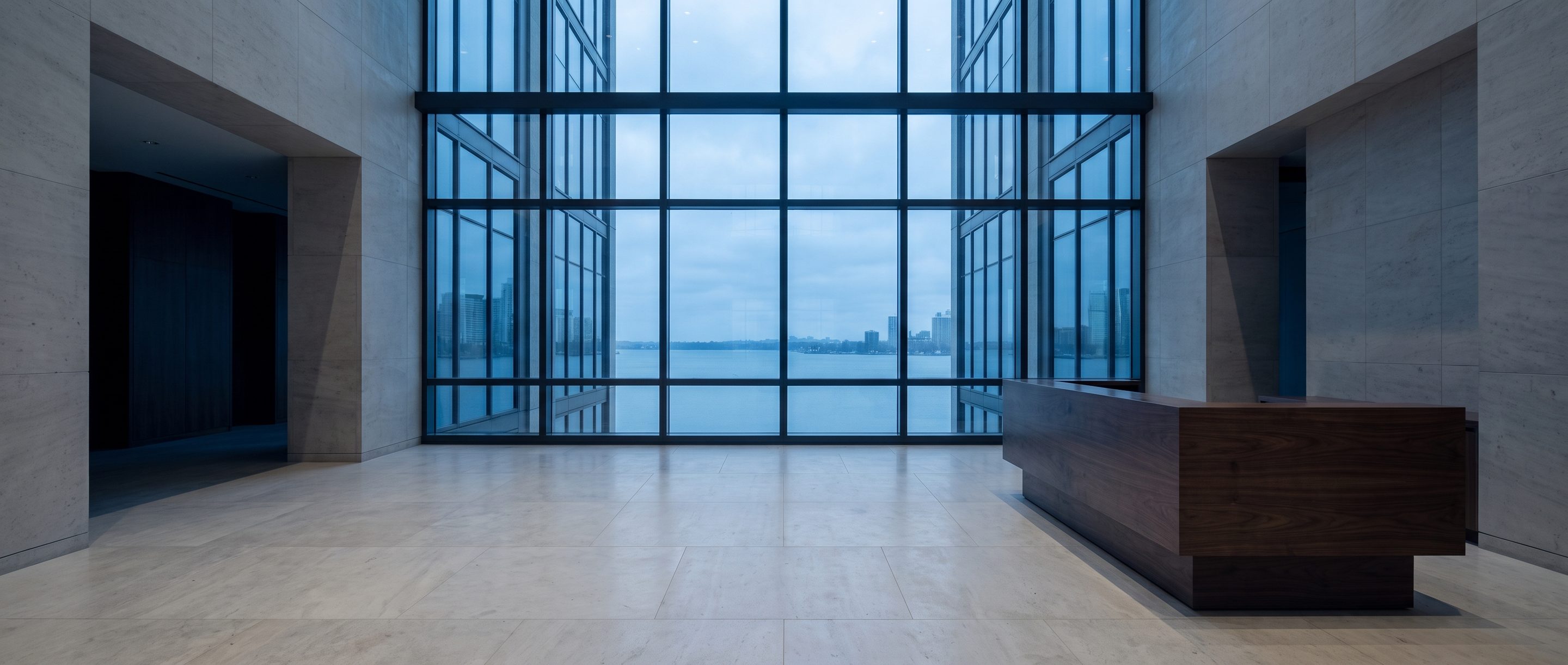 A quiet stone-and-glass office lobby, pale limestone floor.