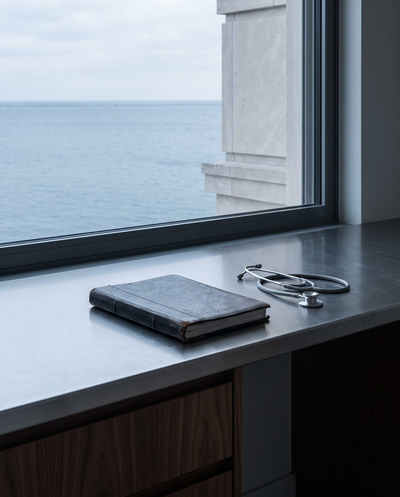 A closed appointment ledger beside a stethoscope on a steel counter.