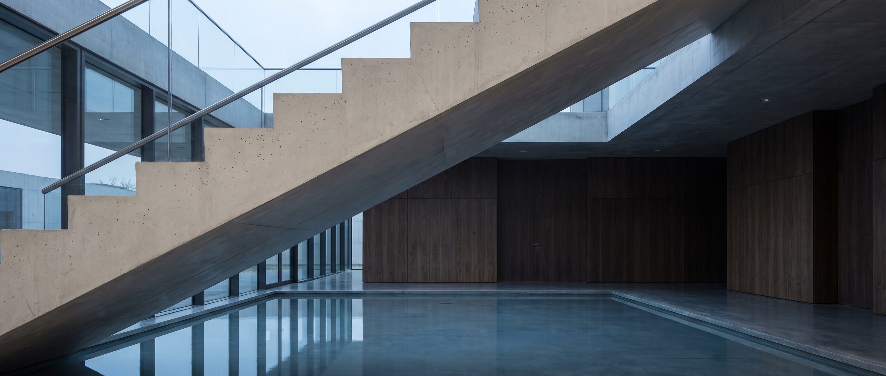 The underside of a pale concrete stair in an empty atrium.