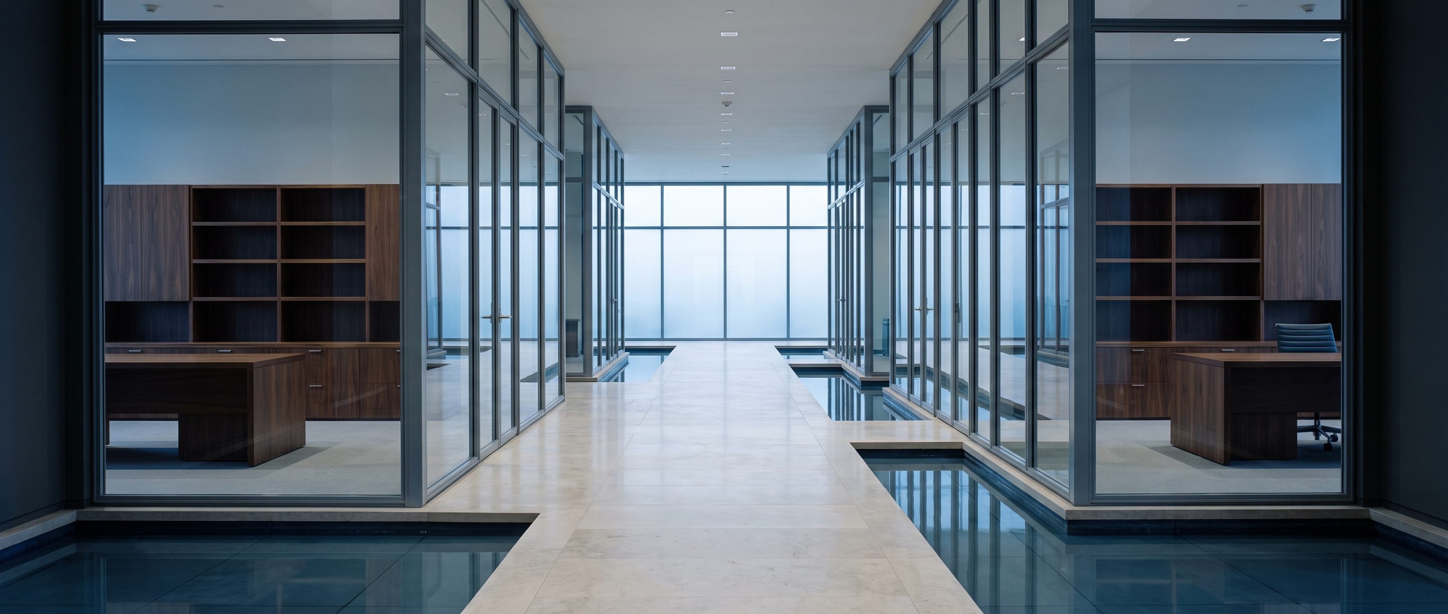 A row of glass-walled meeting rooms along a quiet corridor.