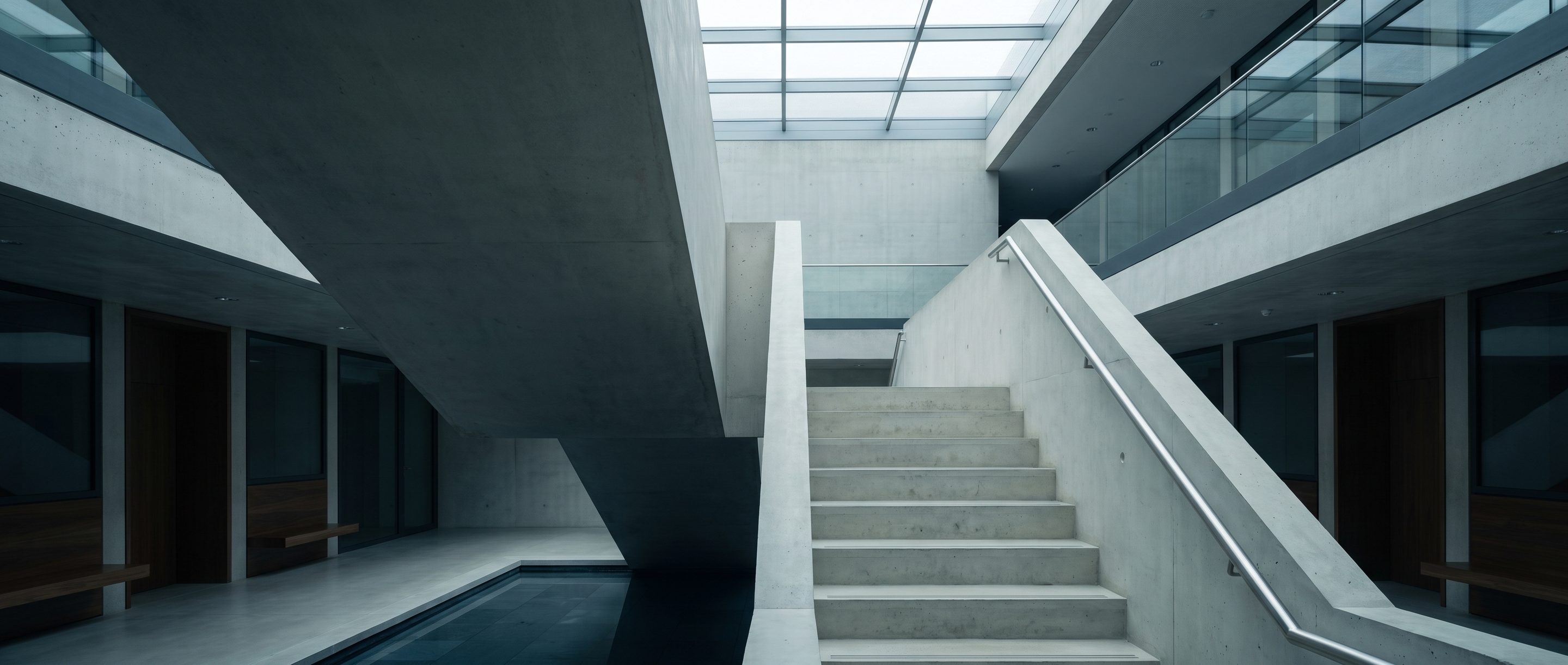The underside of a pale concrete stair in an empty atrium.