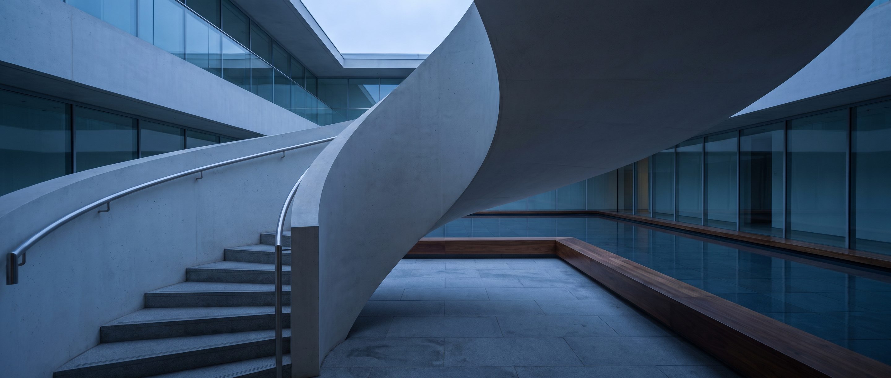 The underside of a pale concrete stair in an empty atrium.