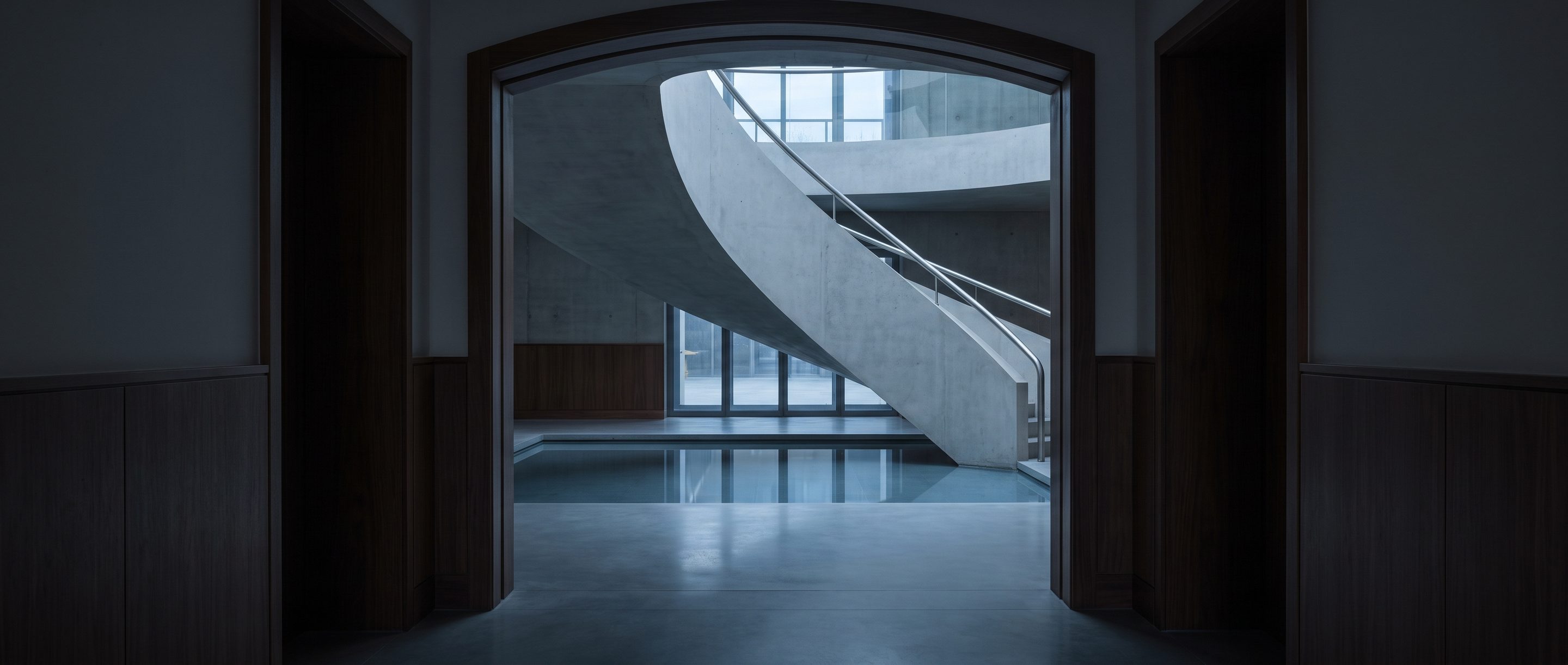 The underside of a pale concrete stair in an empty atrium.