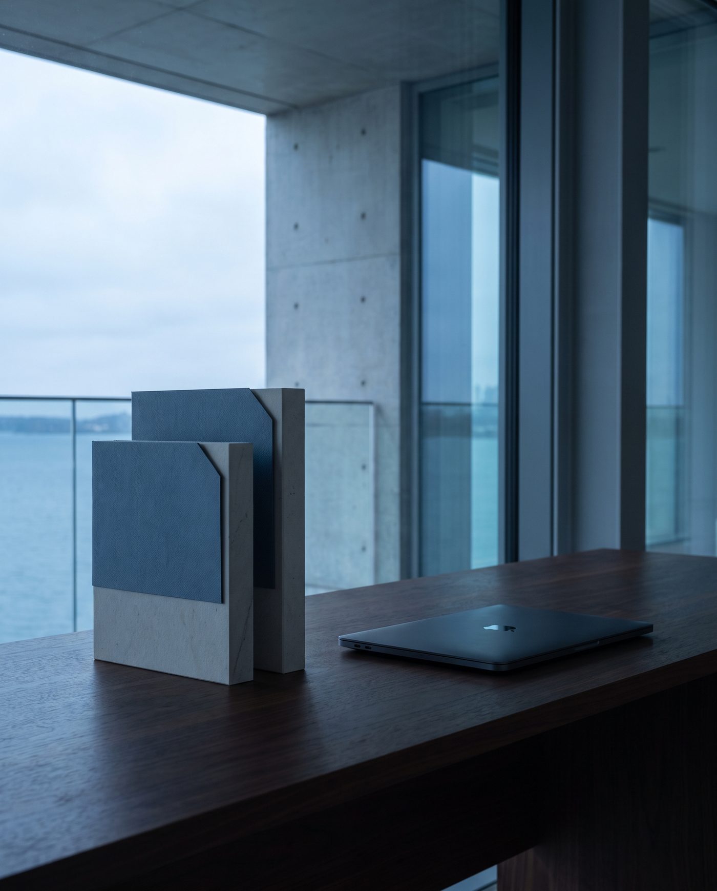 Two identical folders, one slightly taller, beside a closed laptop on a walnut desk.